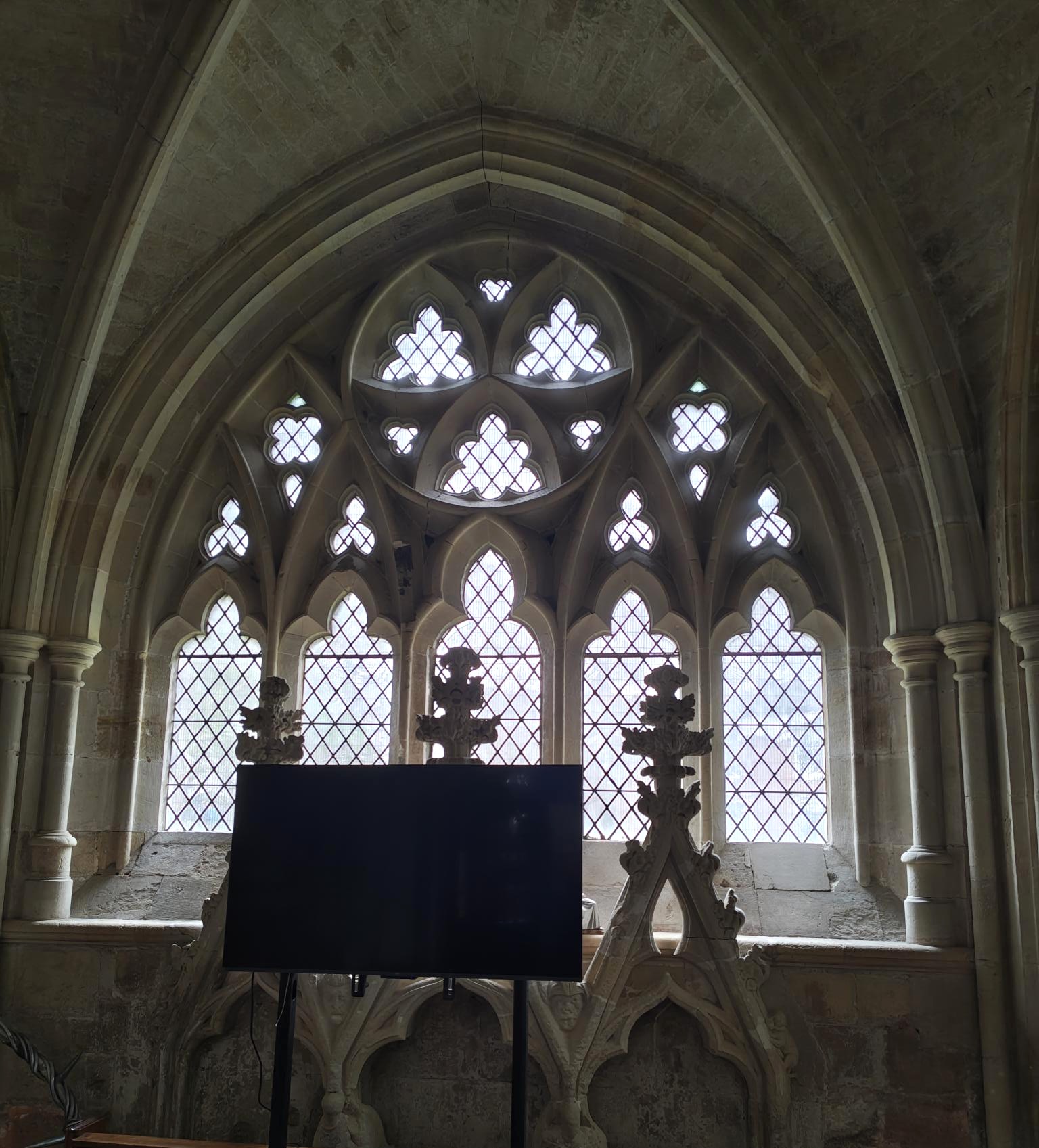 Exeter Stained Glass Window A close-up of Gothic stone window tracery at Exeter Cathedral, showing intricate heart-shaped and trefoil cut-outs against light-filled leaded glass.