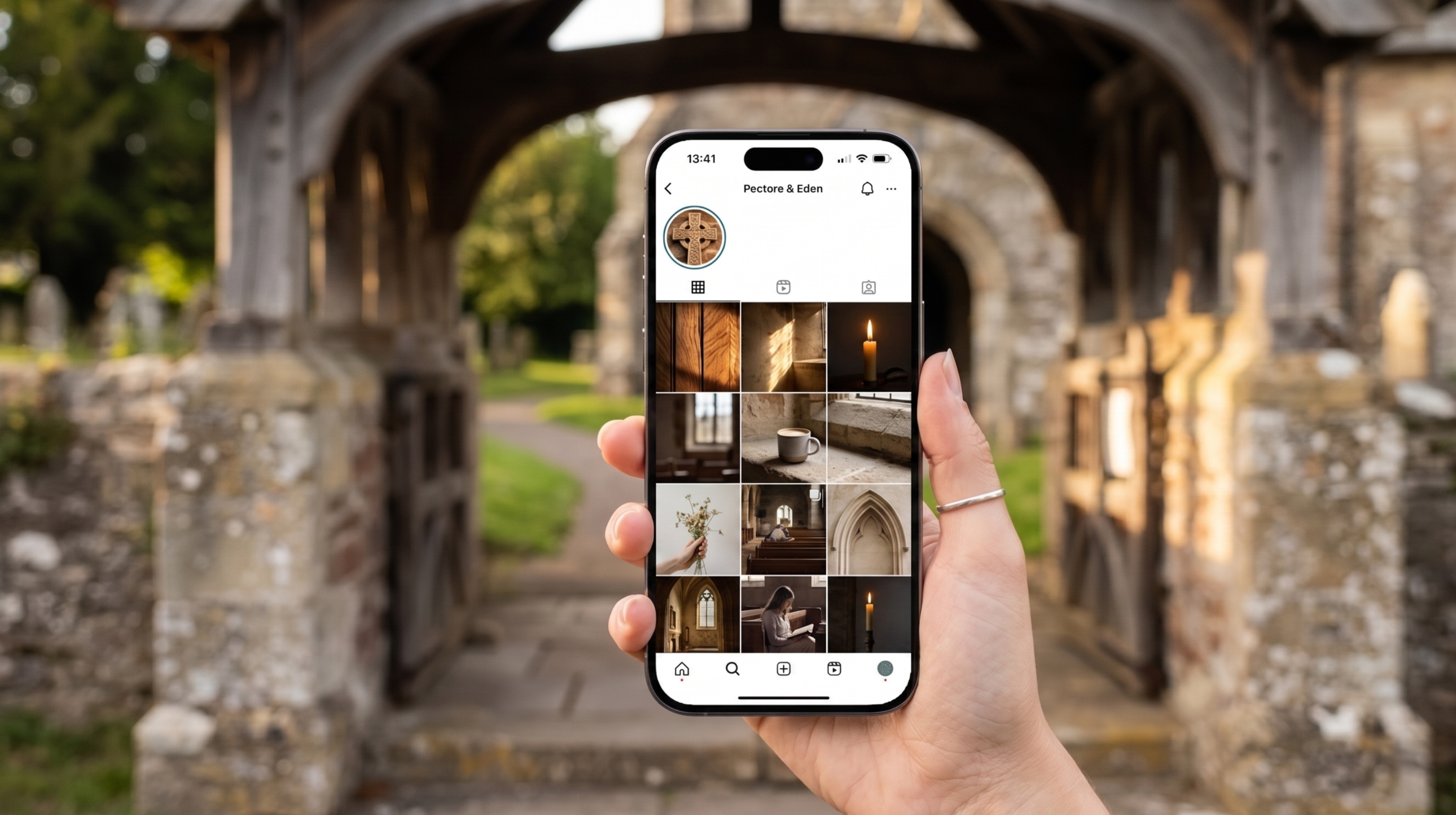 The Digital Porch Your Instagram is the New Lychgate A first-person view of a hand holding a smartphone in front of a blurred, historic stone lychgate entrance to a churchyard. The phone screen shows a curated Instagram grid for "Pectore & Eden." The grid is filled with warm, atmospheric photos: a flickering candle, sunlight hitting a stone pillar, a coffee cup resting on a rustic ledge, and a person reading in a wooden pew. The aesthetic is clean, modern, and serene.